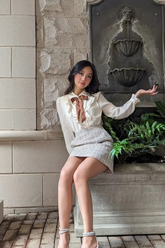 a lady in a white bow tie shirt and a tweed mini skirt